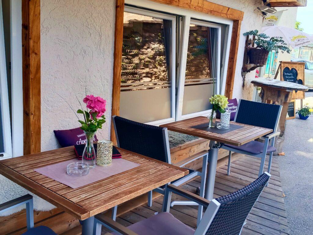 Gemütlicher Außenbereich eines Cafés mit Blumen auf dem Tisch